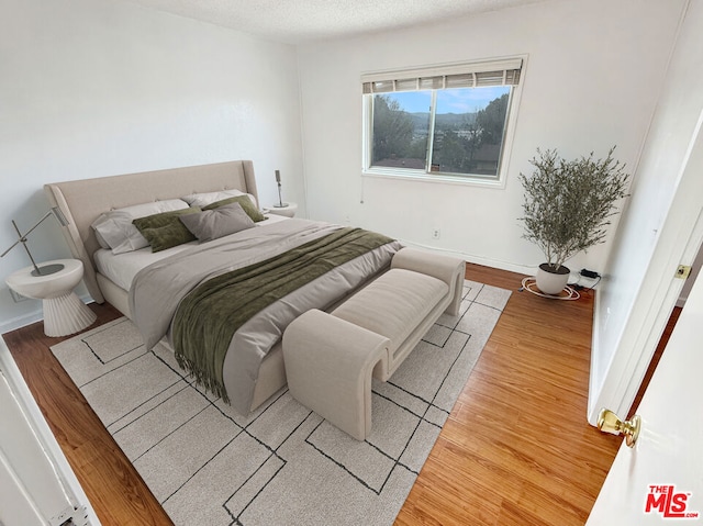 bedroom with light hardwood / wood-style floors and a textured ceiling