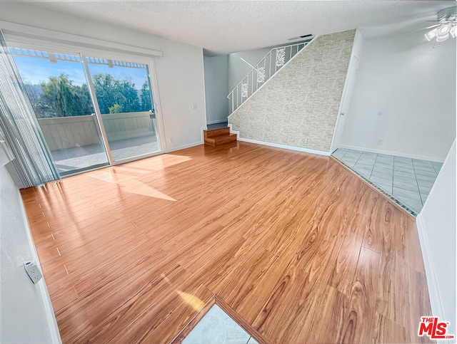 unfurnished room with ceiling fan, hardwood / wood-style floors, and a textured ceiling