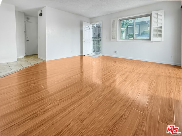 unfurnished room featuring a textured ceiling and light wood-type flooring