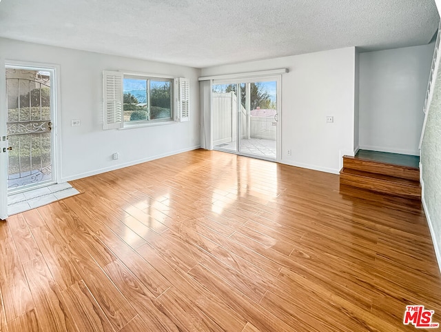 empty room featuring a textured ceiling and light hardwood / wood-style floors