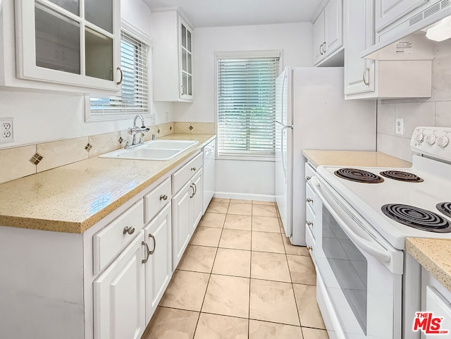 kitchen featuring sink, white appliances, light tile patterned floors, white cabinets, and decorative backsplash