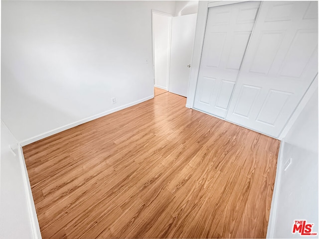 unfurnished bedroom with a closet and light wood-type flooring