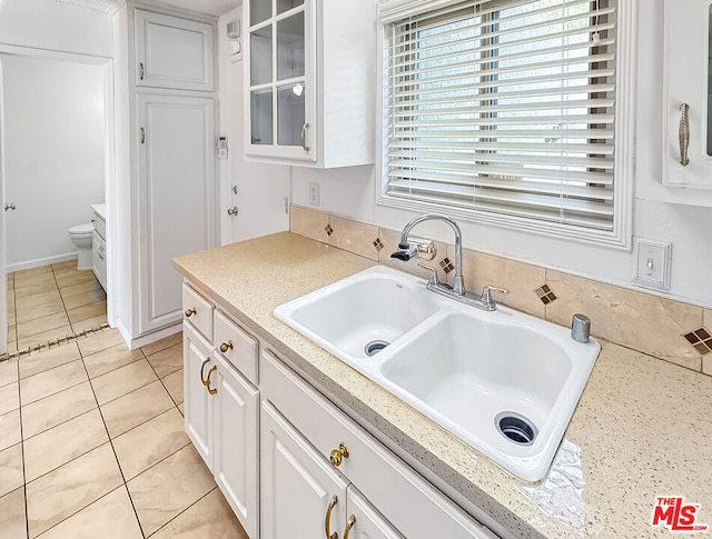 kitchen featuring sink, light tile patterned floors, and white cabinets