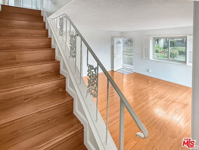 stairs with hardwood / wood-style flooring and a textured ceiling