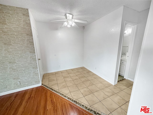 empty room with ceiling fan and a textured ceiling