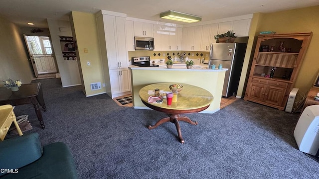 2713 Antonio Dr Unit 104, Camarillo, CA 93010 - kitchen with stainless steel appliances, white cabinetry, dark colored carpet, a center island, and light countertops