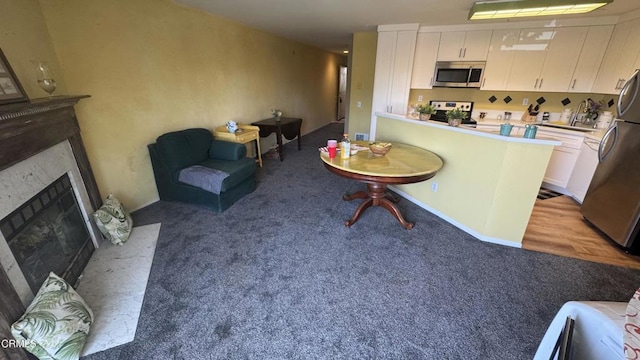 2713 Antonio Dr Unit 104, Camarillo, CA 93010 - kitchen featuring appliances with stainless steel finishes, light carpet, white cabinets, a fireplace with flush hearth, and open floor plan