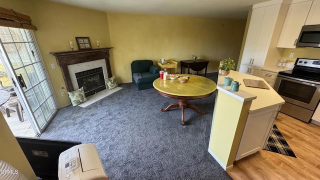 2713 Antonio Dr Unit 104, Camarillo, CA 93010 - kitchen featuring appliances with stainless steel finishes, white cabinetry, light wood finished floors, light countertops, and a fireplace