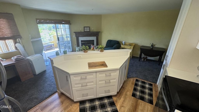 2713 Antonio Dr Unit 104, Camarillo, CA 93010 - kitchen featuring a fireplace, light countertops, wood finished floors, a center island, and white cabinetry