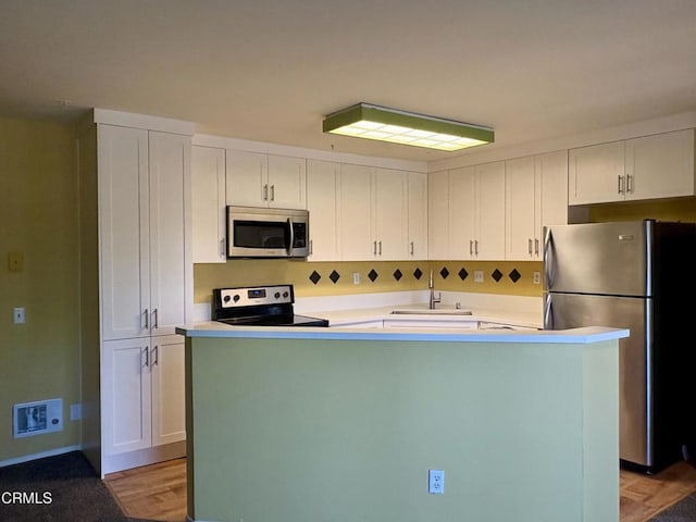 2713 Antonio Dr Unit 104, Camarillo, CA 93010 - kitchen with stainless steel appliances, white cabinetry, light countertops, a center island, and light wood-style flooring