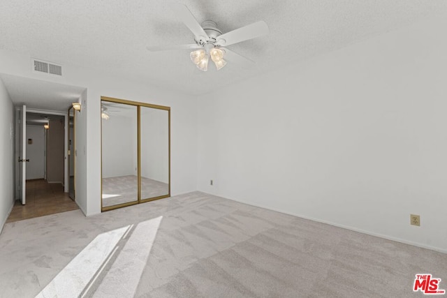 unfurnished bedroom with light colored carpet, a textured ceiling, and a closet