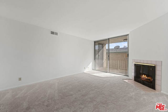 unfurnished living room featuring light colored carpet, a fireplace, and a wall of windows