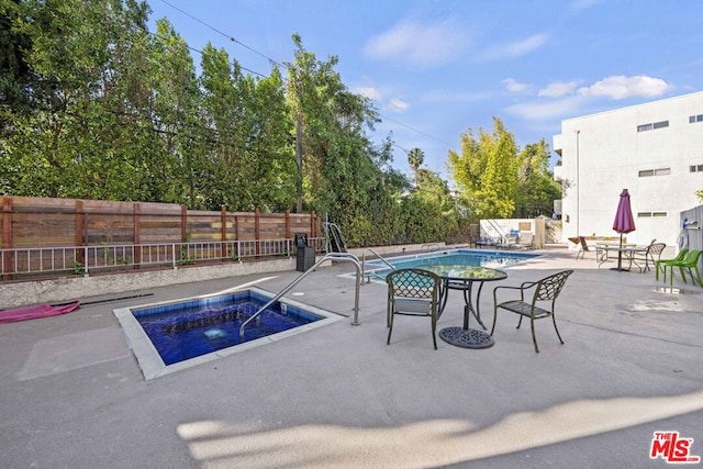 view of pool with a hot tub and a patio