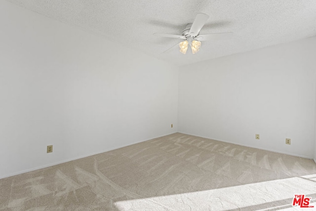 carpeted empty room featuring ceiling fan and a textured ceiling