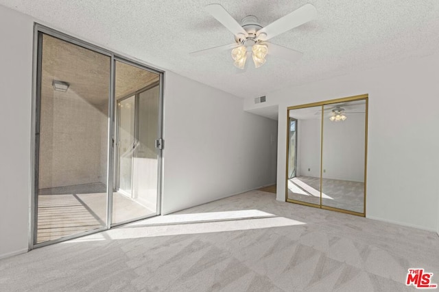 unfurnished bedroom with light carpet, ceiling fan, floor to ceiling windows, and a textured ceiling