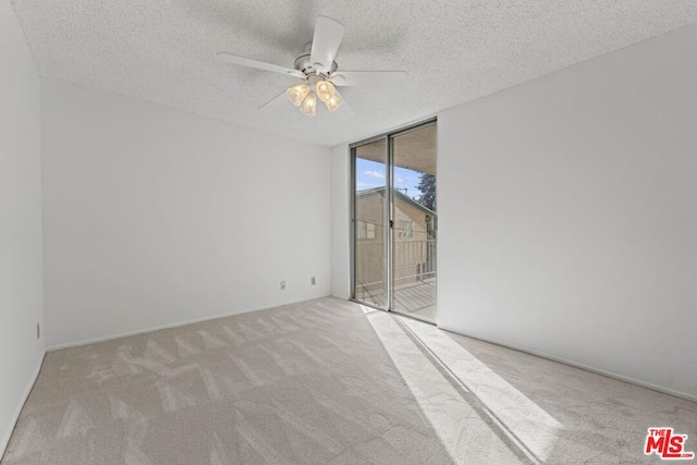 carpeted empty room with a textured ceiling, a wall of windows, and ceiling fan