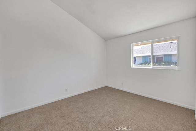 carpeted spare room featuring vaulted ceiling