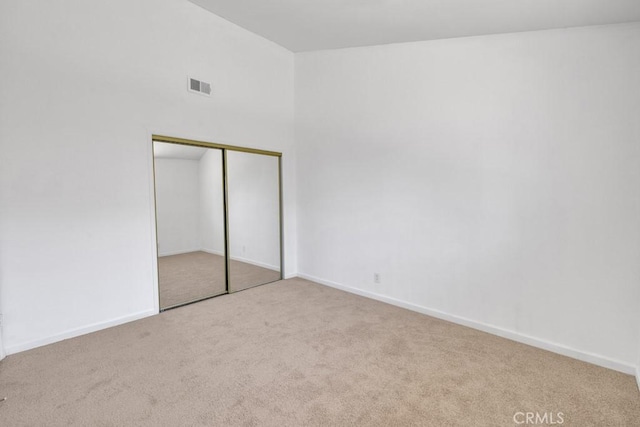 unfurnished bedroom featuring a towering ceiling, light carpet, and a closet