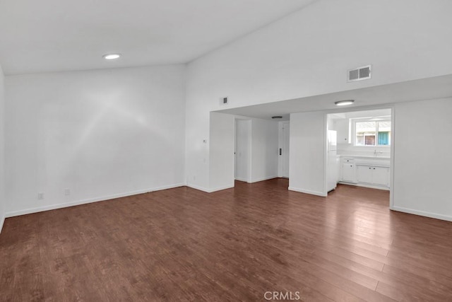 unfurnished living room with dark wood-type flooring and high vaulted ceiling