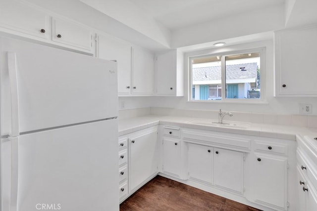 kitchen featuring white refrigerator, dark wood-type flooring, sink, and white cabinets