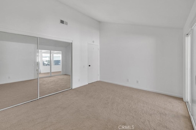 unfurnished bedroom featuring vaulted ceiling and light colored carpet