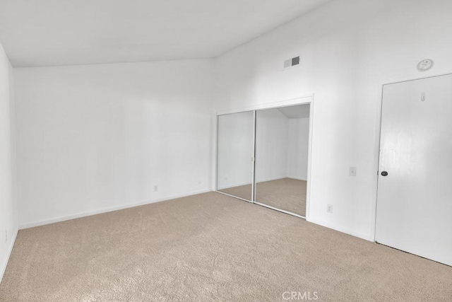 unfurnished bedroom featuring carpet, lofted ceiling, and a closet