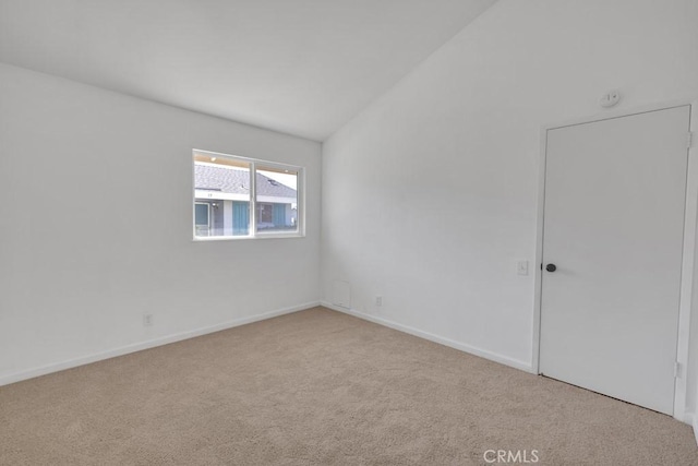 carpeted empty room with vaulted ceiling