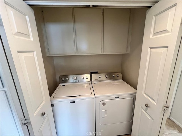 clothes washing area featuring separate washer and dryer and cabinets