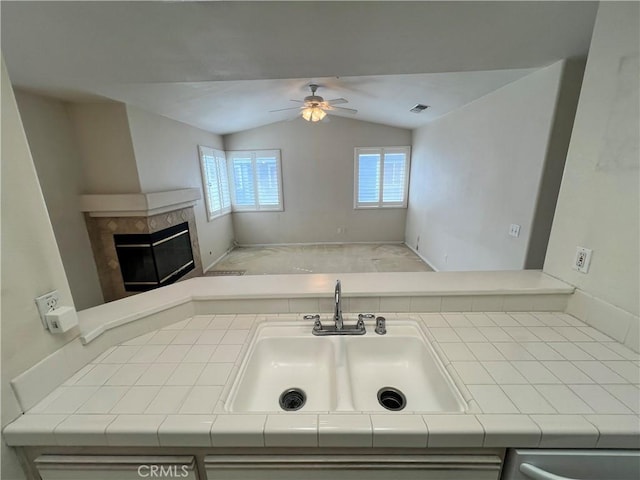 bathroom with ceiling fan, lofted ceiling, a fireplace, and sink