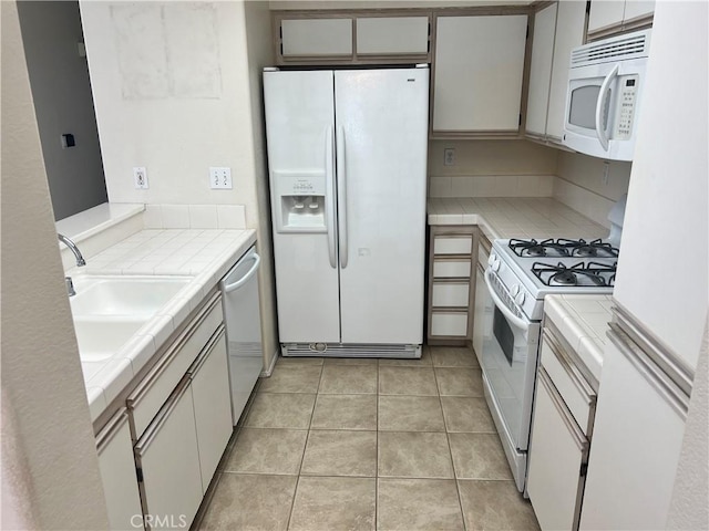 kitchen with white cabinetry, tile countertops, white appliances, and light tile patterned floors