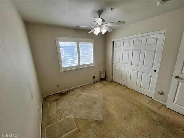 unfurnished bedroom featuring ceiling fan, a closet, and light carpet