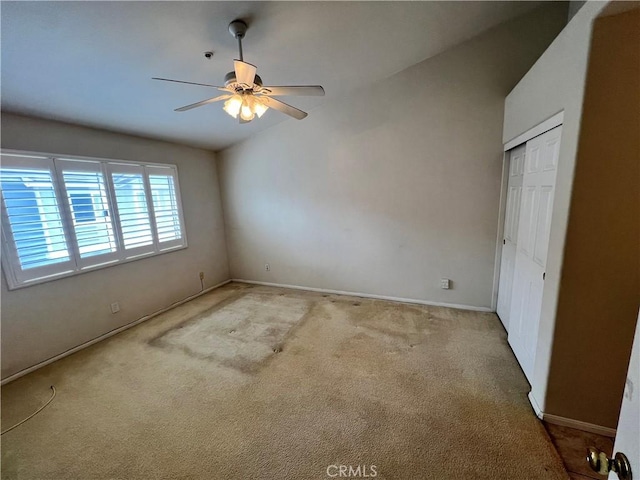 unfurnished bedroom with light carpet, lofted ceiling, a closet, and ceiling fan