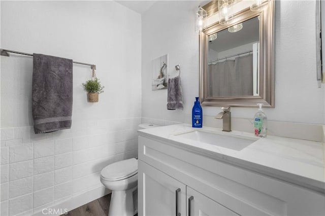 bathroom featuring vanity, toilet, hardwood / wood-style floors, and tile walls