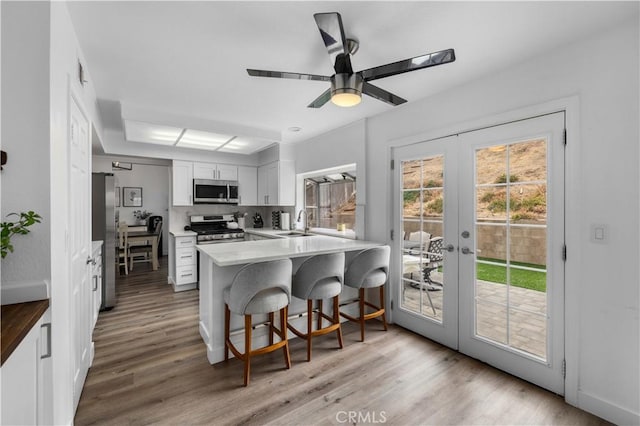 kitchen featuring sink, white cabinets, a kitchen bar, kitchen peninsula, and stainless steel appliances