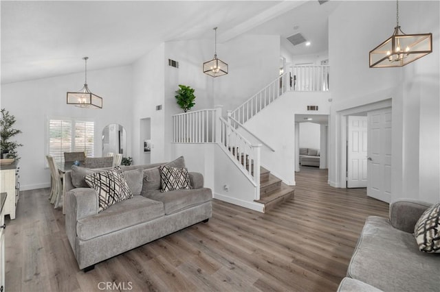 living room with hardwood / wood-style flooring, high vaulted ceiling, and a notable chandelier