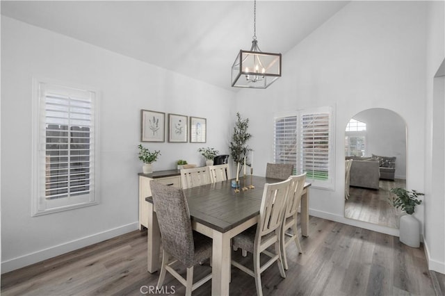 dining space featuring a notable chandelier, hardwood / wood-style flooring, and high vaulted ceiling