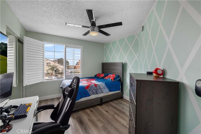 bedroom with ceiling fan, a textured ceiling, and light wood-type flooring