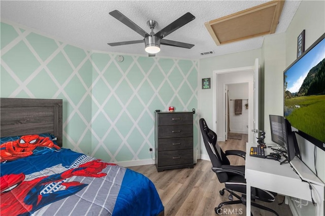 bedroom with ceiling fan, a textured ceiling, and light hardwood / wood-style flooring