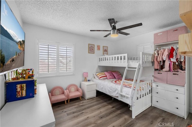 bedroom with ceiling fan, dark wood-type flooring, and a textured ceiling