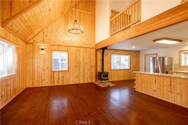 unfurnished living room featuring a wood stove, dark hardwood / wood-style floors, and wood walls