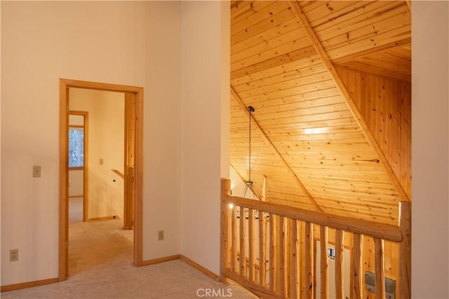 hallway with a towering ceiling, light carpet, and wood ceiling