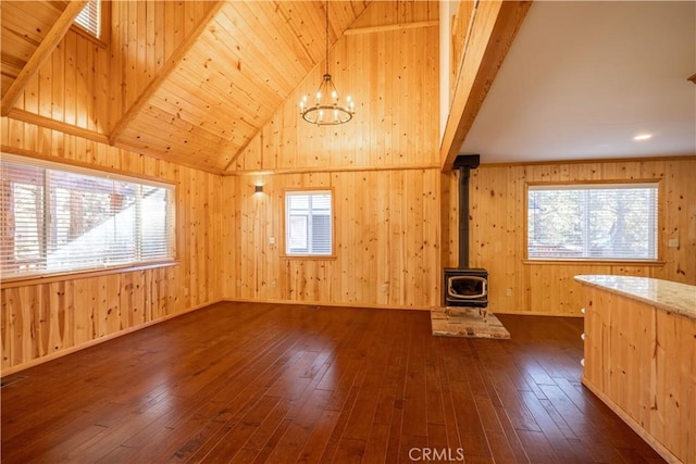 additional living space with high vaulted ceiling, dark hardwood / wood-style floors, a wealth of natural light, and a wood stove