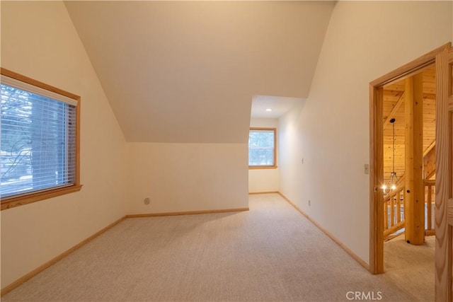 additional living space featuring vaulted ceiling and light colored carpet