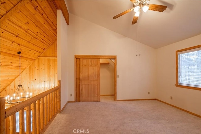 carpeted empty room with beamed ceiling, ceiling fan with notable chandelier, and high vaulted ceiling