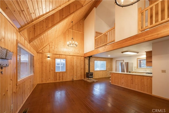 unfurnished living room with a wood stove, dark hardwood / wood-style floors, and wood walls