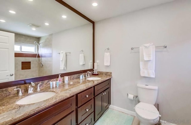 bathroom with vanity, toilet, and a tile shower