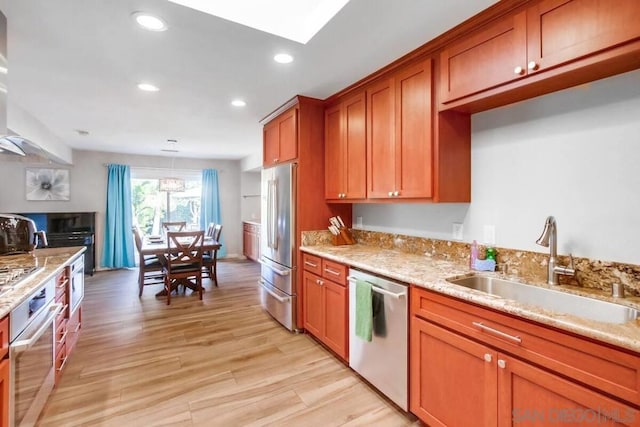 kitchen with pendant lighting, sink, light hardwood / wood-style flooring, stainless steel appliances, and light stone countertops