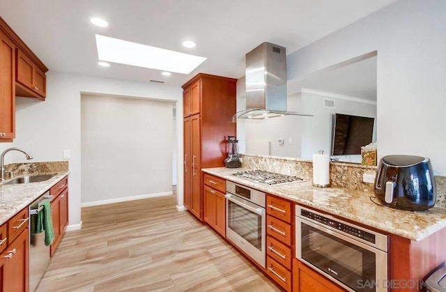 kitchen featuring sink, light hardwood / wood-style flooring, appliances with stainless steel finishes, light stone counters, and island range hood