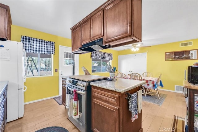 kitchen featuring stainless steel range with gas cooktop, white fridge, ceiling fan, light stone countertops, and light hardwood / wood-style floors