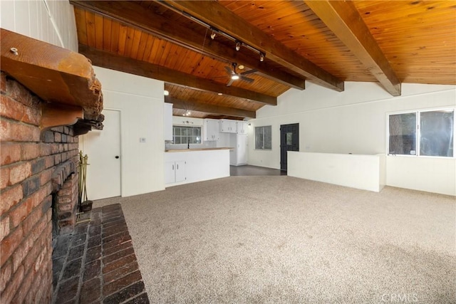 unfurnished living room featuring lofted ceiling with beams, carpet flooring, a fireplace, wood ceiling, and ceiling fan